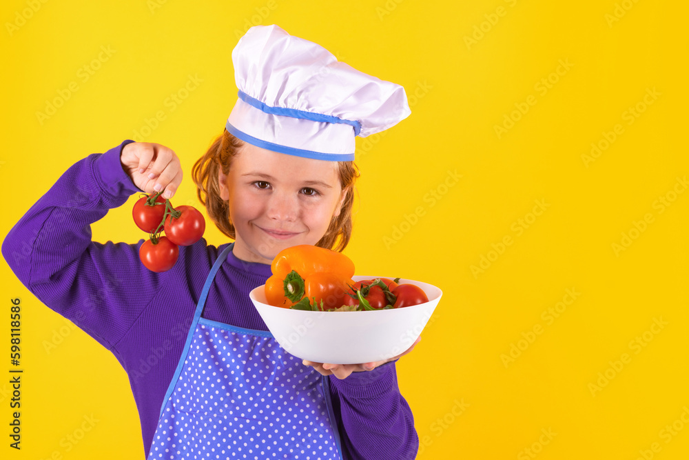 Kid cook hold tomato. Excited chef cook. Child wearing cooker uniform and chef hat preparing food, studio portrait. Kid cook hold tomato. Excited chef cook. Child wearing cooker uniform and chef hat preparing food, studio portrait.