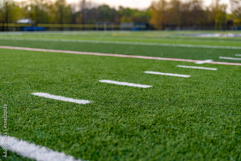 Late afternoon close up photo of hash marks on a synthetic turf football field.