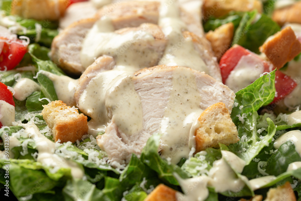 A delicious chicken caesar salad with parmesan cheese, tomatoes, croutons and dressing