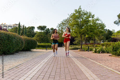 Two Energetic Young Women Running in the Park