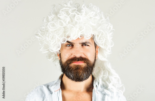 Bearded man in white wig. Smiling man with beard and mustache in curly wig. Bearded hipster in wig. Man in periwig. Party time. Fashion concept. Barbershop advertise. Stylish guy with long white hair.