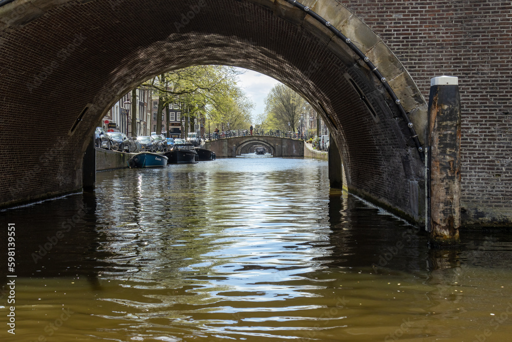 Amsterdam canals with arched bridges in the spring, dutch boat cruises looking through the bridges