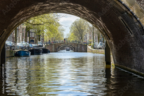 Amsterdam canals with arched bridges in the spring, dutch boat cruises looking t Fototapeta