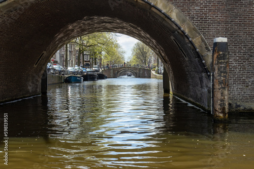 Amsterdam canals with arched bridges in the spring, dutch boat cruises looking through the bridges © Sarah