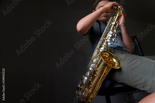 Young boy practicing playing the saxophone instrument at home