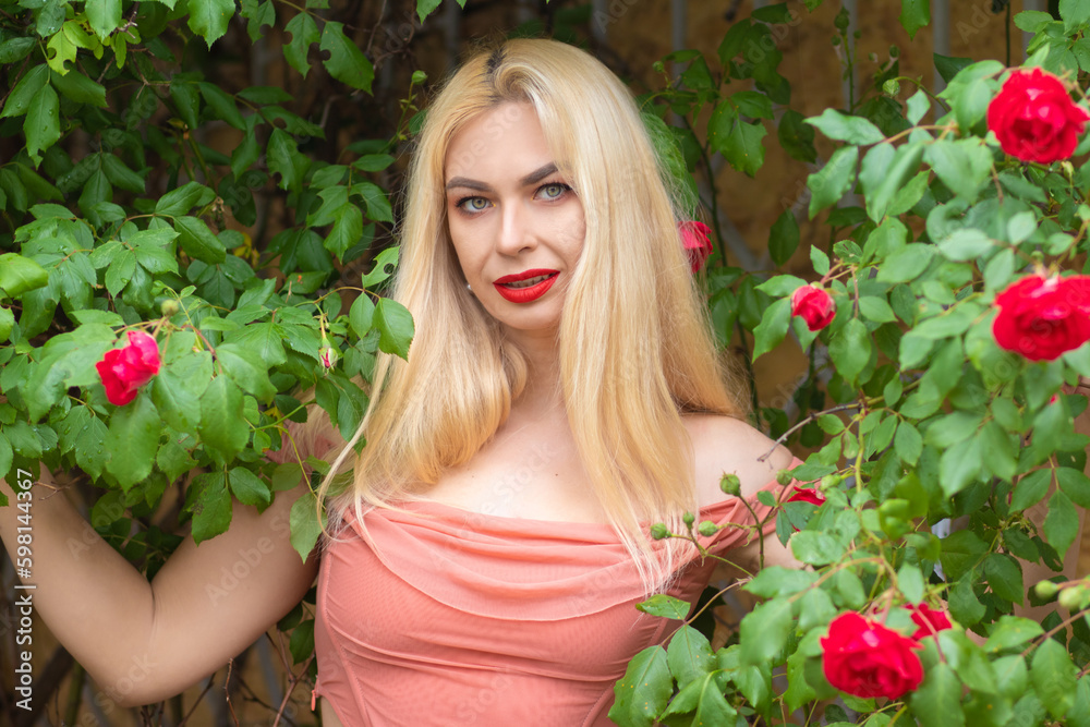 Beautiful woman with long blonde hair and red lips wearing pink clothes