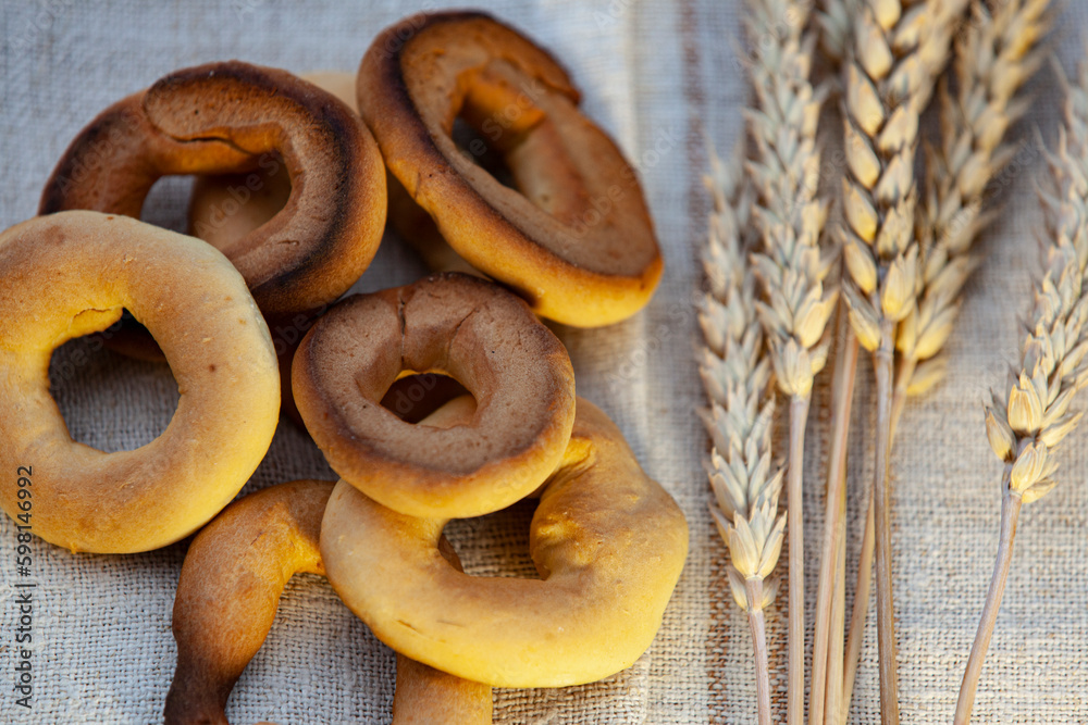 Homemade baking. Dry bagels on a napkin against the background of spikelets of wheat