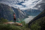 Girl standing on top of Eidfjord in Norway, looking over the fjord and mountains
