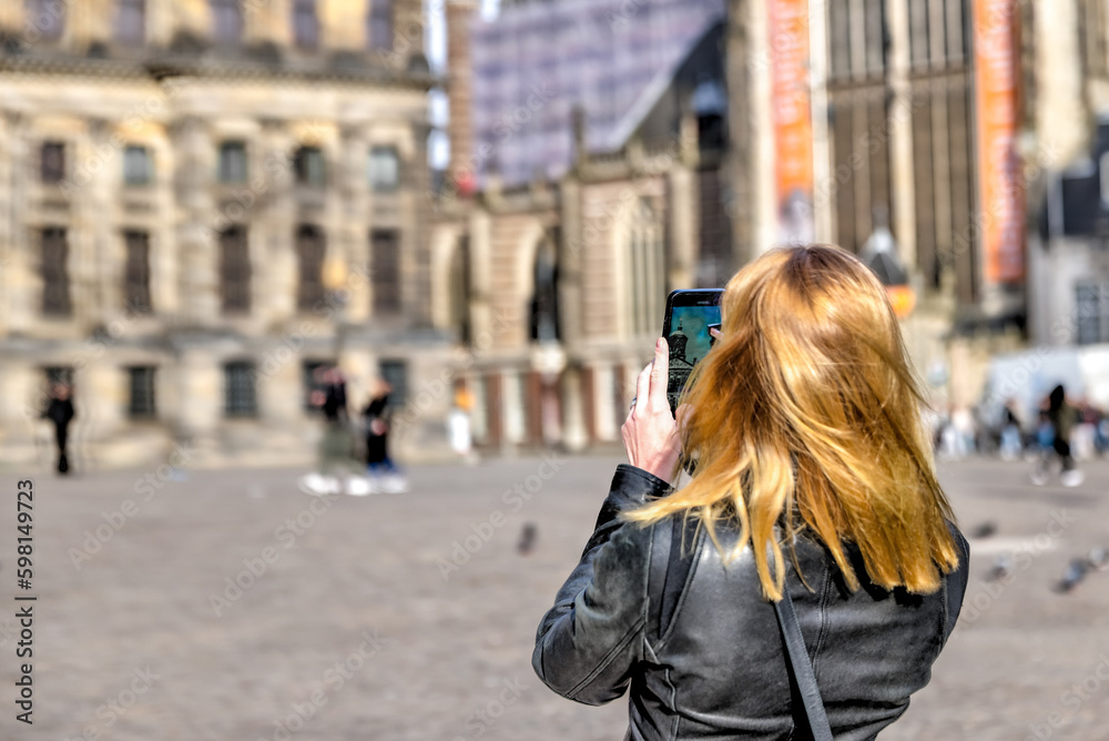 Blonde woman taking a photo in Dam Square in Amsterdam
