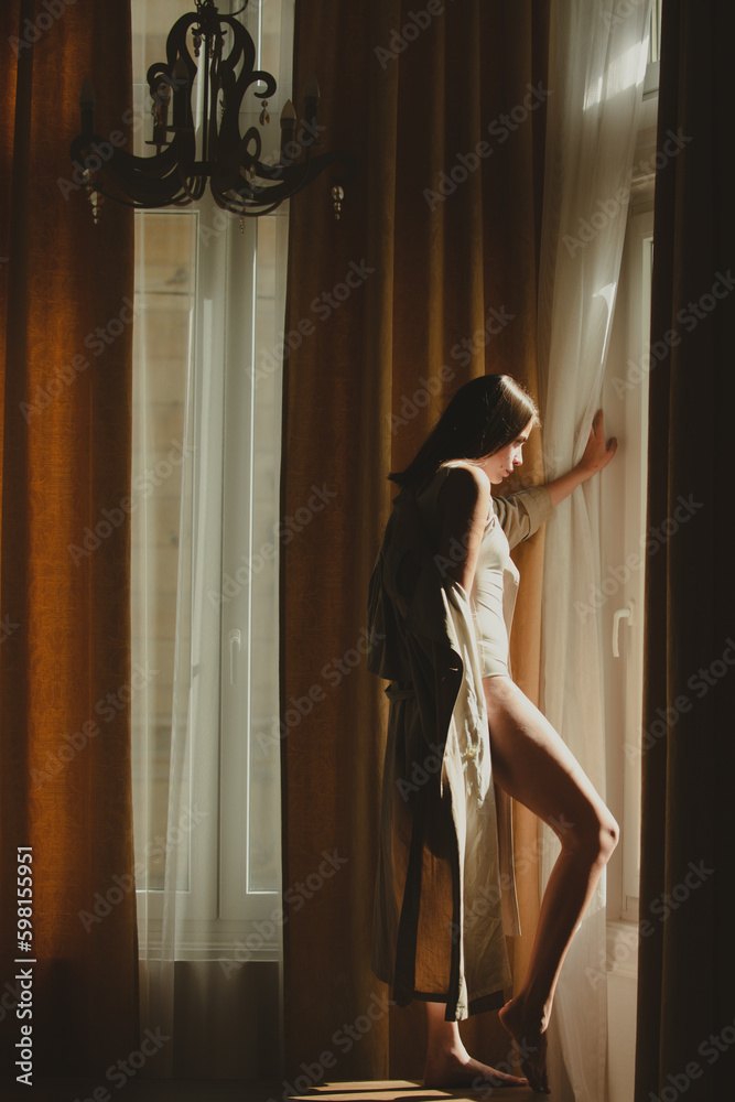 Fashion woman sexy and sensual in luxury apartment posing on window curtains. Sexy attractive woman posing with slim sexy body. Beautiful sexy model portrait.