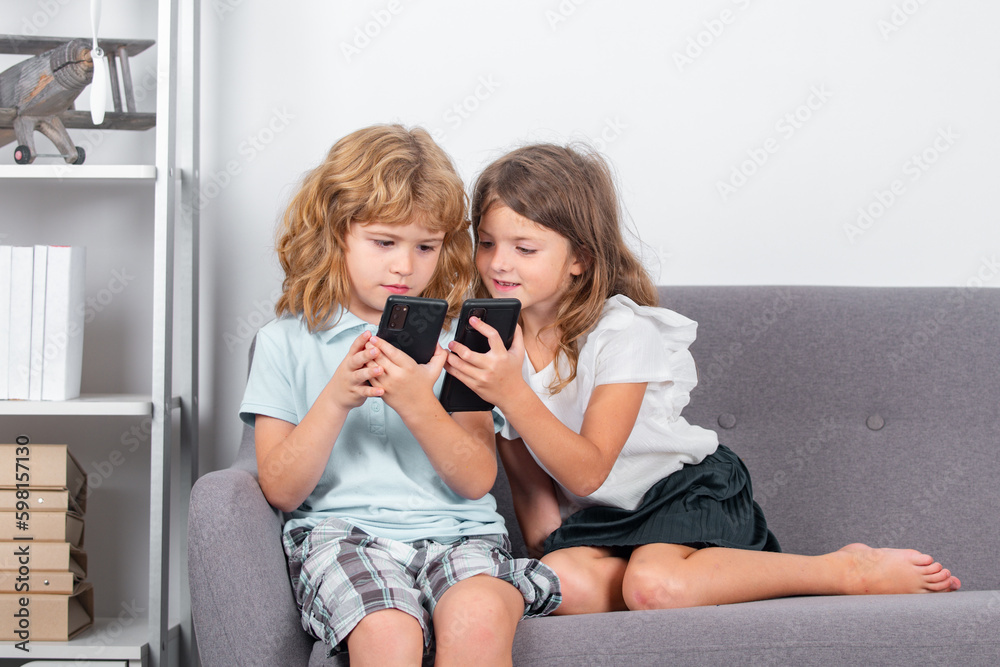 Kids playing smartphone. Brother and sister at home playing video games. Two siblings brother sister at home alone using mobile phone. Children playing video games on gadget. Social media addiction.
