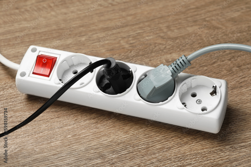 Power strip with extension cord on wooden floor, closeup. Electrician's equipment Power strip with extension cord on wooden floor, closeup. Electrician's equipment