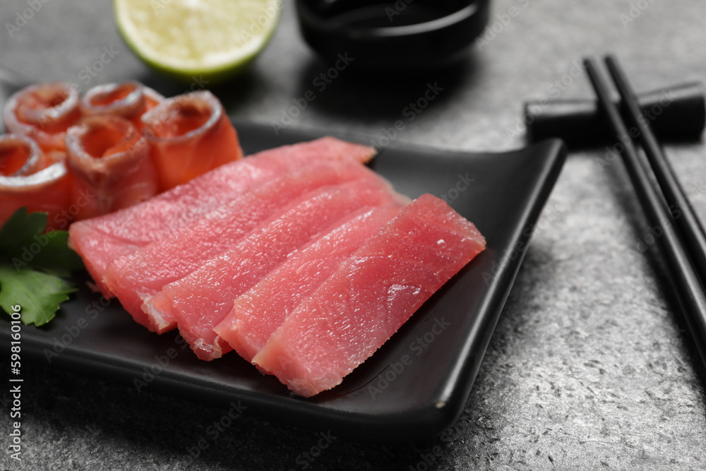 Sashimi set (raw tuna and salmon slices) with parsley on grey table, closeup Sashimi set (raw tuna and salmon slices) with parsley on grey table, closeup
