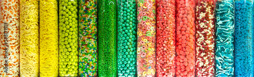 Transparent plastic tubes full of colorful candies. Rainbow jelly