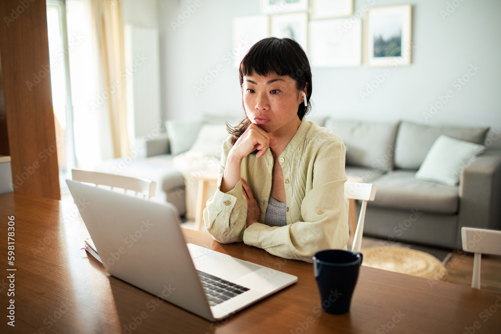 Young Japanese Woman working on a laptop in the kitchen Young Japanese Woman working on a laptop in the kitchen