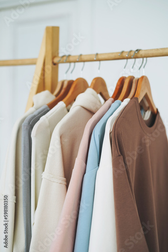 Сotton tops sweatshirts in natural tones on wooden shelf in bright room