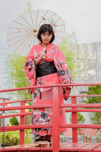 Photo of a young woman wearing a kimono and a wagasa umbrella against a backdrop of cherry blossoms