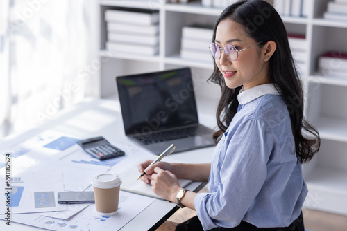 Asian Business woman using calculator and laptop for doing math finance on an office desk, tax, report, accounting, statistics, and analytical research concept 