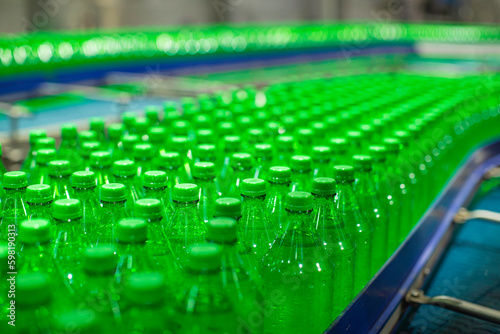 Beverage factory interior. Conveyor flowing with bottles for juice green