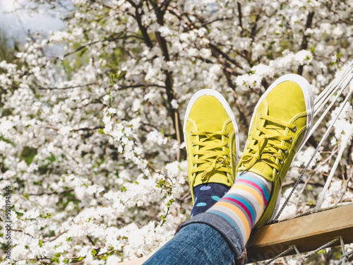 Trendy sneakers and colorful socks on the background of flowering trees. Closeup, outdoors. Men's and women's fashion style. Beauty and elegance concept © Svetlana