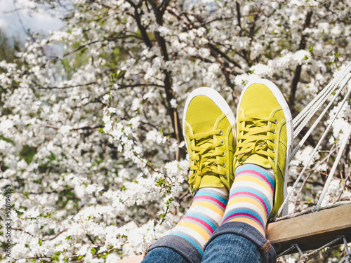 Trendy sneakers and colorful socks on the background of flowering trees. Closeup, outdoors. Men's and women's fashion style. Beauty and elegance concept © Svetlana