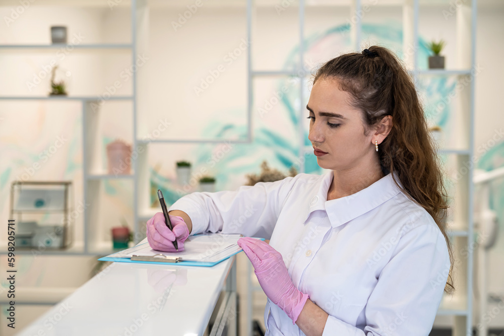 Obraz premium young nurse fills out a client card at the register.