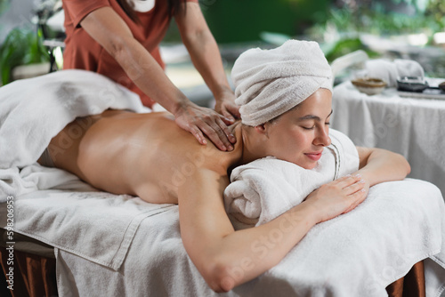 Beautiful caucasian woman having shoulder massage at night spa salon 