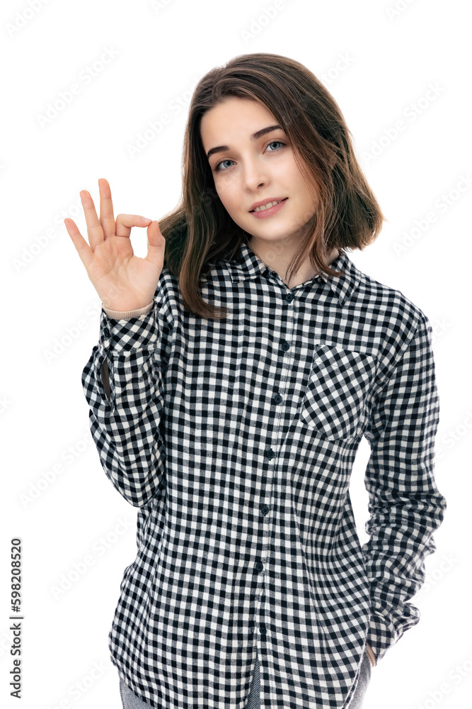 Portrait of brunette eighteen year old girl shows ok okay gesture, isolated on white background. Young caucasian woman with hand in pocket smiling on camera and posing in studio. Portrait of brunette eighteen year old girl shows ok okay gesture, isolated on white background. Young caucasian woman with hand in pocket smiling on camera and posing in studio.