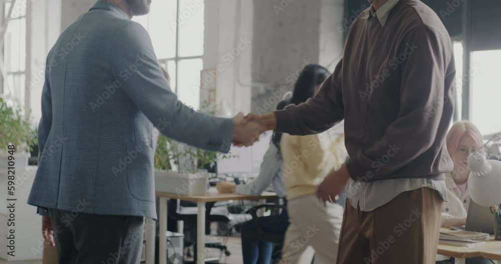 Men colleagues talking then shaking hands enjoying cooperation in modern coworking center. Businesspeople and communication concept. Generative AI