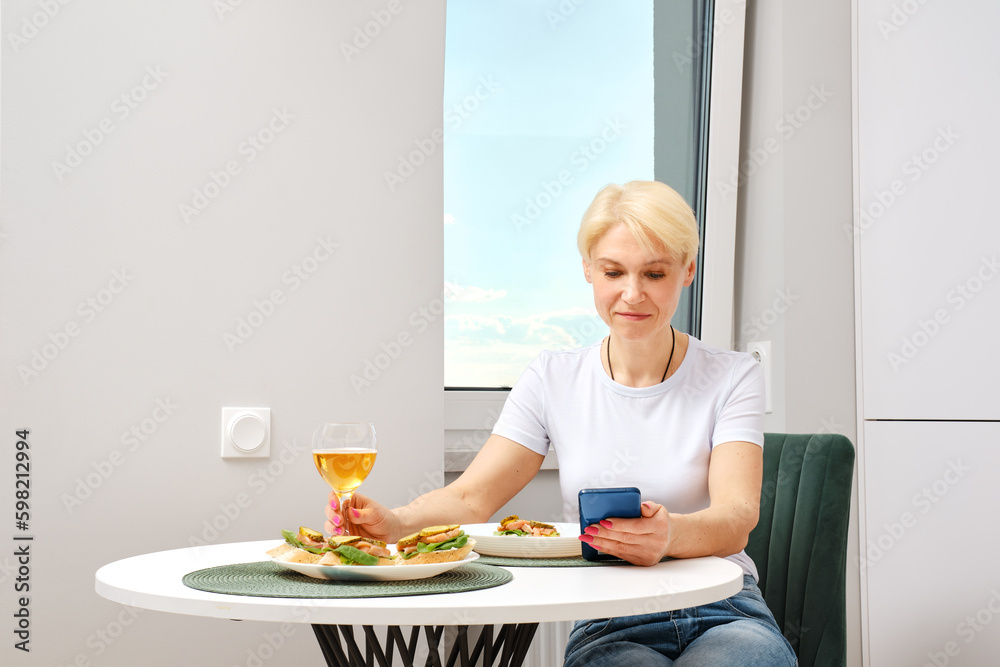 Senior woman reading news from smartphone while having breakfast