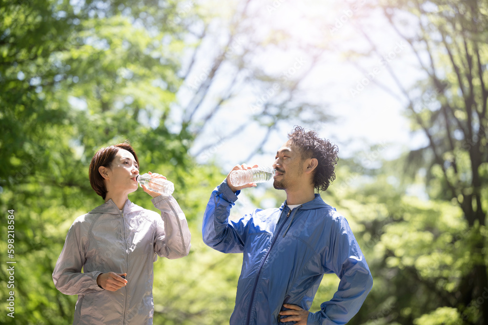 Naklejka premium Two middle couples drinking water in a park with fresh greenery, running in sportswear, etc.
