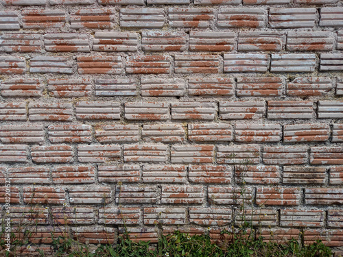 Texture of old brick wall with grass underneath as a background for interior, exterior decoration and design.