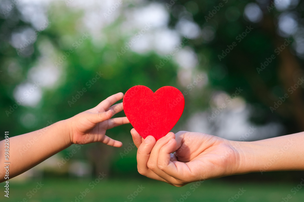 people, age, family, love and health care concept - close up of senior woman and baby hands holding red heart over green natural background. new generation save the world and earth day concept.