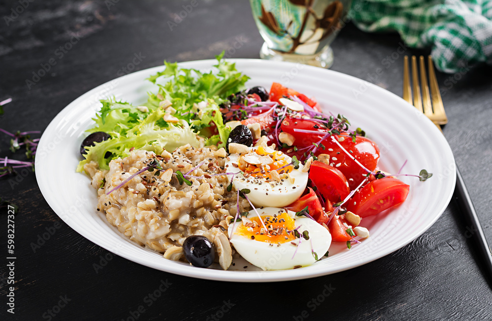 Breakfast oatmeal porridge with boiled egg, cherry tomatoes, olives, nuts and microgreens. Healthy balanced food. Breakfast oatmeal porridge with boiled egg, cherry tomatoes, olives, nuts and microgreens. Healthy balanced food.