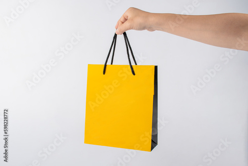 Yellow paper bags in hand for shopping isolated on white background