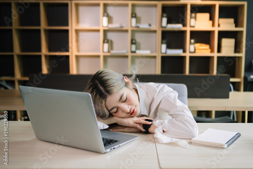 Asian woman feeling migraine head strain.Overworked businesswoman financier while working on laptop and tablet at office.