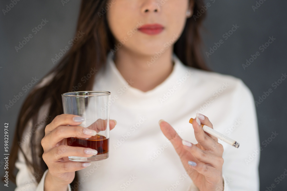 Asian woman hand drinking glass of alcohol and smoking cigarette Asian woman hand drinking glass of alcohol and smoking cigarette