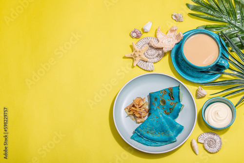A cup of coffee and blue thin pancakes in a marine style. Starfish, sea shells, palm leaves