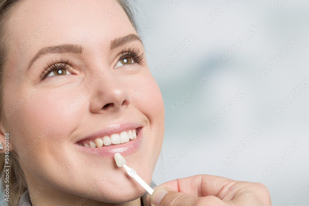 Close up of dentist hand using shade guide at woman's mouth to check veneer of teeth for bleaching Close up of dentist hand using shade guide at woman's mouth to check veneer of teeth for bleaching