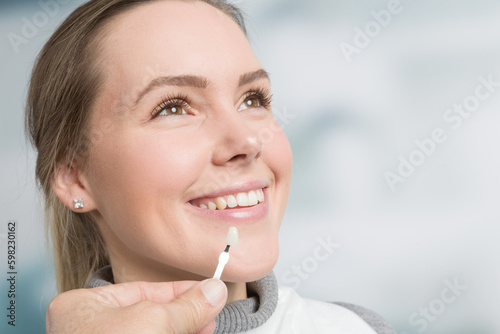Close up of dentist hand using shade guide at woman's mouth to check veneer of teeth for bleaching