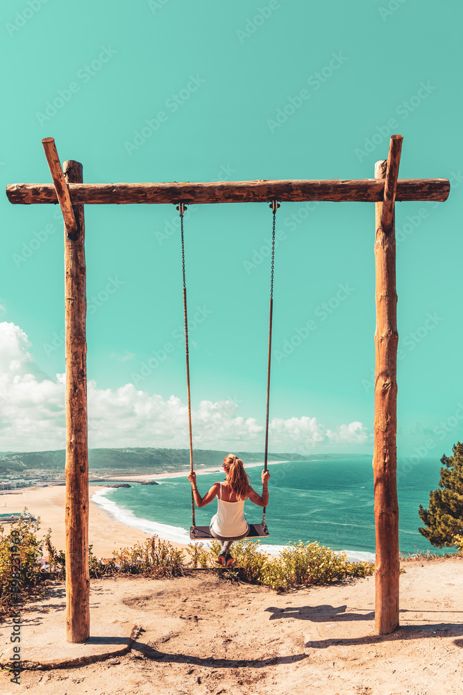 Woman swinging on swing enjoying beautiful ocean panoramic view- Portugal Woman swinging on swing enjoying beautiful ocean panoramic view- Portugal