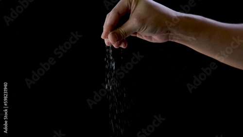 Man's hands are sprinkling salt on food on a black background	
