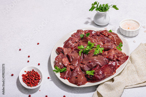 Raw chicken liver on stone background. Fresh ingredients ready for cooking, parsley, red pepper