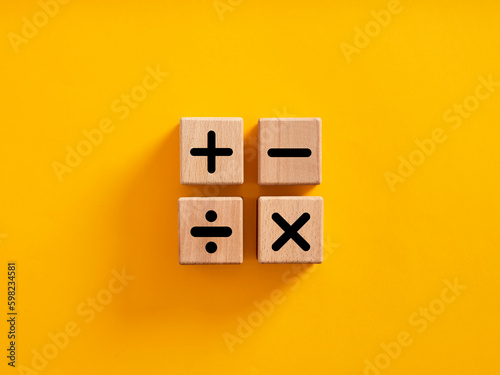 Basic mathematical operations symbols. Plus, minus, multiply and divide symbols on wooden cubes on yellow background.