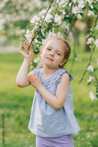 Child girl holds a branch in a blooming spring garden