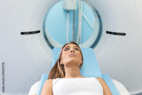 Woman Undergoing CT Scan While Doctor's Using Computers. Patient lying on the TC scanner bed waiting to be scanned. photo