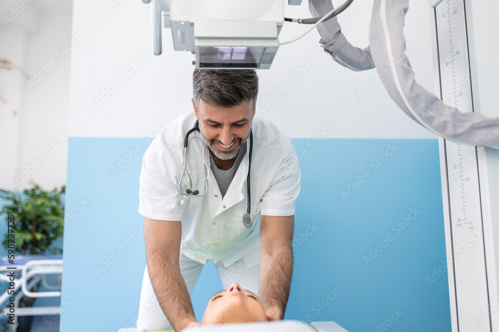 Multiethnic radiologists with young female patient in x-ray room, Radiologist setting up the machine to x-ray female patient