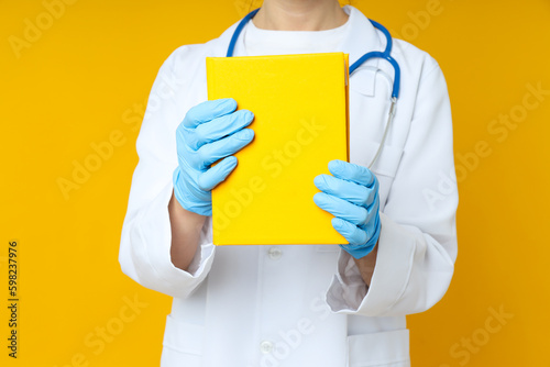 Female doctor holds yellow book on yellow background