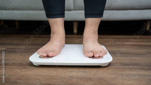 Fat diet and scale feet standing on electronic scales for weight control. Measurement instrument in kilogram for a diet control.