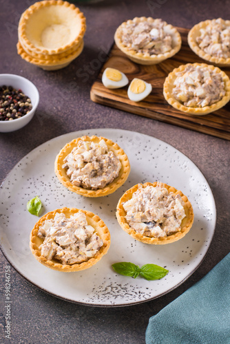 Tartlets filled with canned fish, eggs and mayonnaise on a plate vertical view